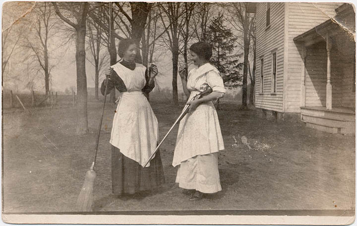 Della with a broom and Lula Mae Mathews with shotgun eating cake