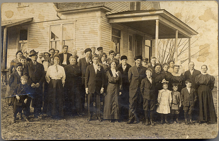 Over thirty people take part in a wedding photo with some of the Hurelle and Peck families.